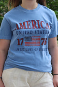 Blue t-shirt with 'America United States 1776 Sweet Land of Liberty' text and American flag design.